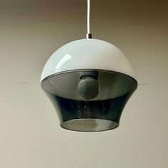 a white and black light fixture hanging from a ceiling in a room with gray walls