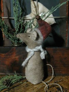 a stuffed mouse sitting on top of a wooden table next to a potted plant