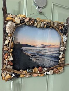 a frame made out of driftwood and rocks hanging on the wall next to a door