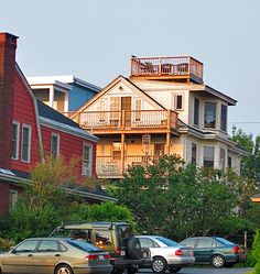 several cars parked on the side of a road in front of some houses with balconies