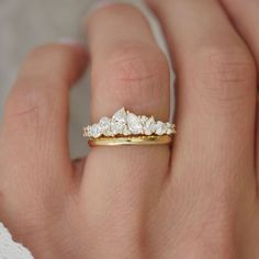 a woman's hand holding a gold ring with three diamonds on it and the middle one has a five stone diamond band