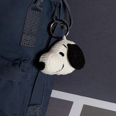 a small stuffed dog hanging from the side of a bag with a keychain