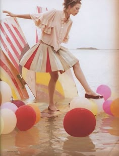 a woman standing in the water surrounded by balloons