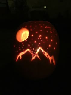 a pumpkin carved to look like mountains with the moon in the sky and stars on it