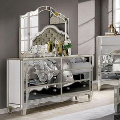 a bedroom scene with focus on the bed and mirrored dresser in the foreground,