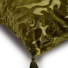 a close up of a pillow with a tassel on the bottom and an ornate design