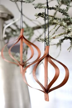 two metal ornaments hanging from a tree with brown ribbon on the top and one is made out of wood