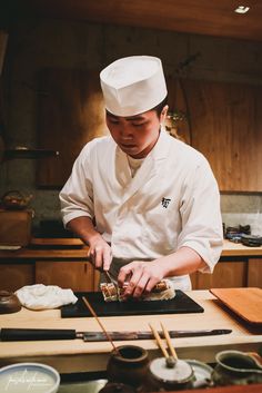 a chef preparing food in a kitchen with chopsticks on the counter and other items