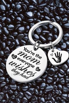 two handprinted metal key chains sitting on top of black rocks with the words, you're the world everyone wants to be here