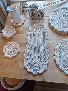 crocheted doily laid out on top of a wooden table next to a vase