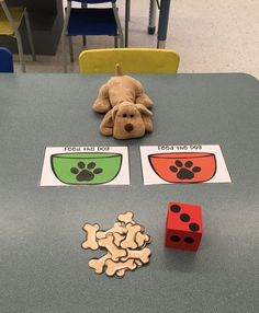 a stuffed dog sitting on top of a table next to two dices and a toy