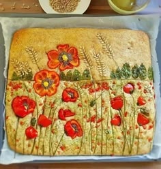 the cake is decorated with red flowers and green leaves on it's side, along with other food items