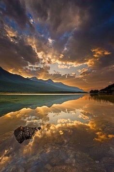 the sky is reflecting in the water and clouds are reflected on the lake's surface