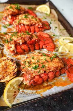 cooked lobsters on a baking sheet with lemon wedges and parmesan cheese