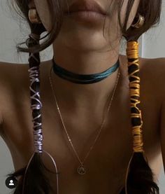 a woman with long hair wearing three necklaces on her neck and two earrings on her chest