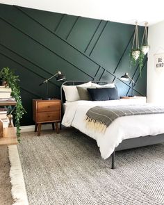 a bed room with a neatly made bed and a green accent on the wall behind it