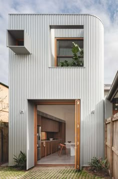 an open door leading into a white house with wooden shutters and brick flooring