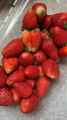 a pile of strawberries sitting on top of a plastic container