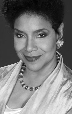 a black and white photo of a woman with short hair wearing a pearled necklace