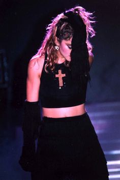 a woman with long hair wearing a black outfit and cross on it's chest