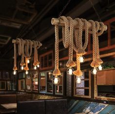 several lights hanging from the ceiling in a restaurant with wood beams and rope around them