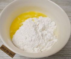 a white bowl filled with flour on top of a wooden table next to a tag