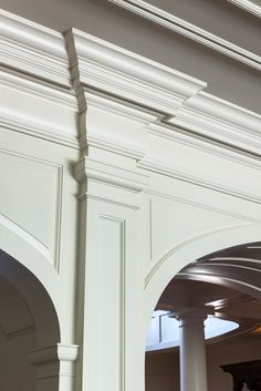 an archway between two white pillars in a room with columns and arches on the ceiling