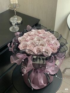 a large bouquet of pink roses sitting on top of a black table next to a mirror