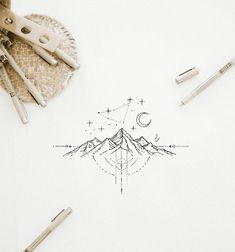 a pen and some scissors on top of a white paper with mountains in the background