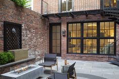 an outdoor patio area with chairs and fire pit in the center, surrounded by brick buildings