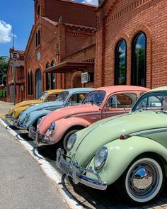 a row of old cars parked in front of a brick building