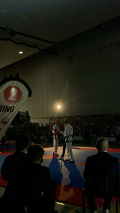 two men standing on top of a blue mat in front of an audience at a competition