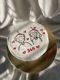 a cake decorated with two people and hearts on it's side sitting on a gold plate