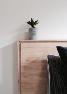 a plant is sitting on top of a wooden shelf next to a pillow and blanket