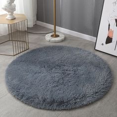 a large round rug is on the floor next to a lamp and pictures in a living room