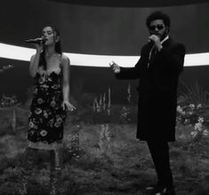 a man and woman singing into microphones while standing in front of an empty stage