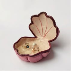 a pink shell shaped box with a pearl in it