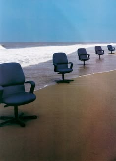 several office chairs sitting on the beach near the ocean