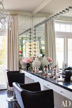 a large mirror sitting above a counter in a room with chairs and chandelier