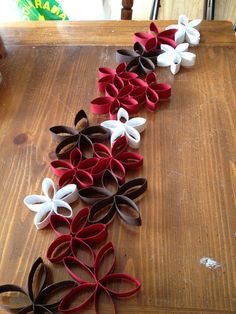 several paper flowers are lined up on a wooden table, ready to be made into decorations