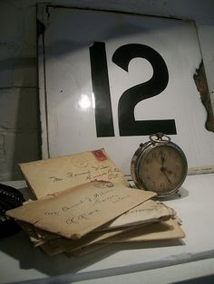 an old clock sitting on top of a table next to some letters and envelopes