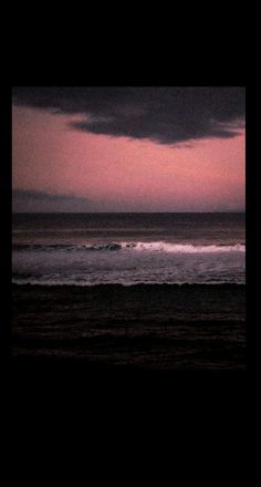 the sun is setting over the ocean with dark clouds