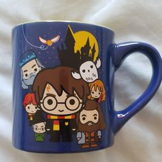 a blue coffee mug with harry potter characters painted on the front and sides, sitting on a white sheet