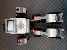 two lego vehicles are shown on the floor, one is white and grey with red accents