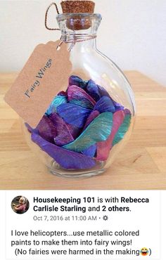 a glass bottle filled with lots of purple and blue feathers sitting on top of a wooden table