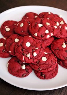 a white plate topped with red cookies covered in white chocolate chips