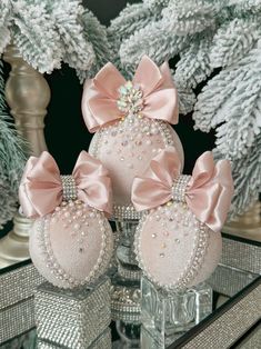 three pink christmas ornaments with bows on them