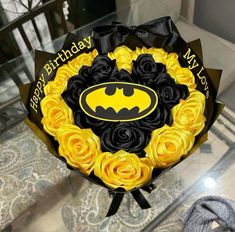 a bouquet of yellow and black roses with a batman logo on it