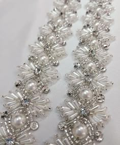 the beaded necklace is made with pearls and swarong crystals on white fabric