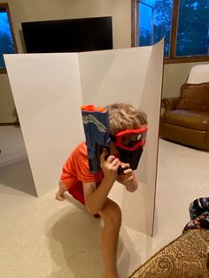 a young boy in an orange shirt and goggles takes a photo with his camera